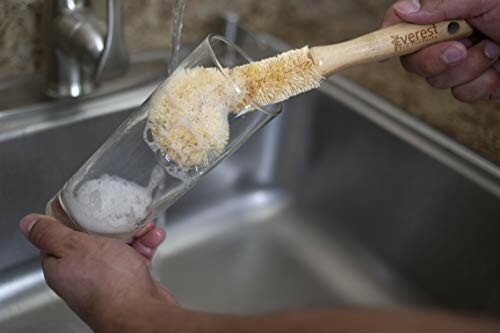 Person cleaning a glass with a bottle brush over a sink.